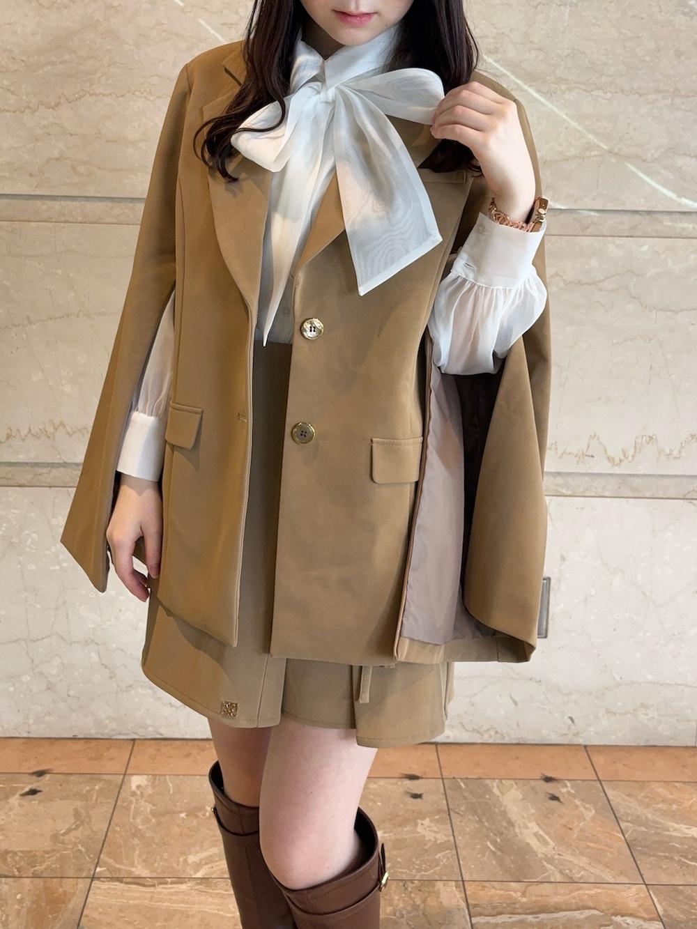 ベージュ系のテーラードジャケット、ベージュ系のスカート、ブラウン系のブーツを着用したレディースの冬コーディネートの5枚目の写真