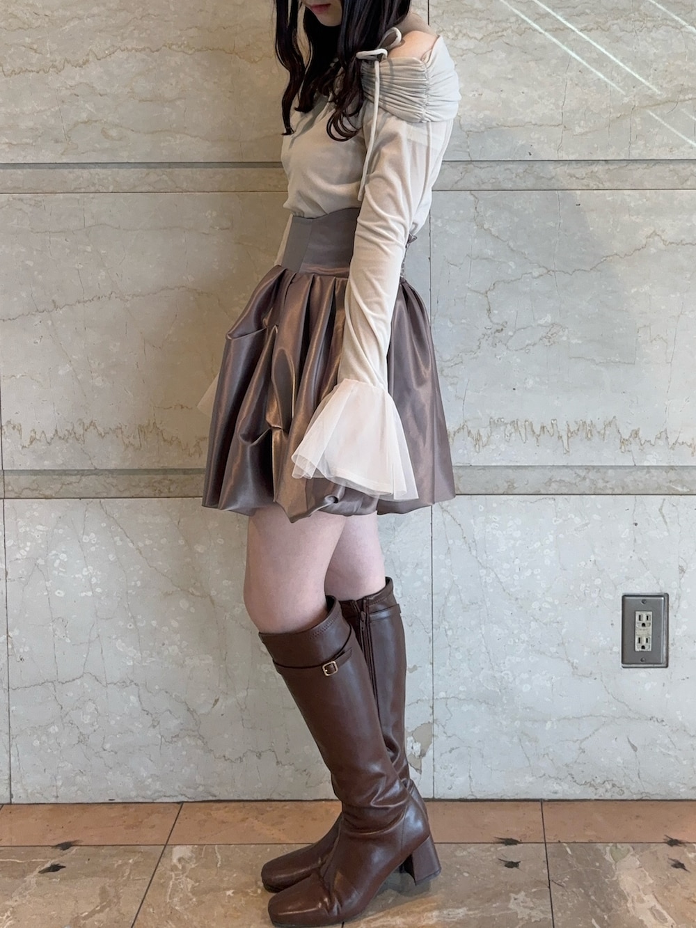 ブラウン系のスカート、ベージュ系のTシャツ/カットソー、ブラウン系のブーツを着用したレディースの冬コーディネートの3枚目の写真