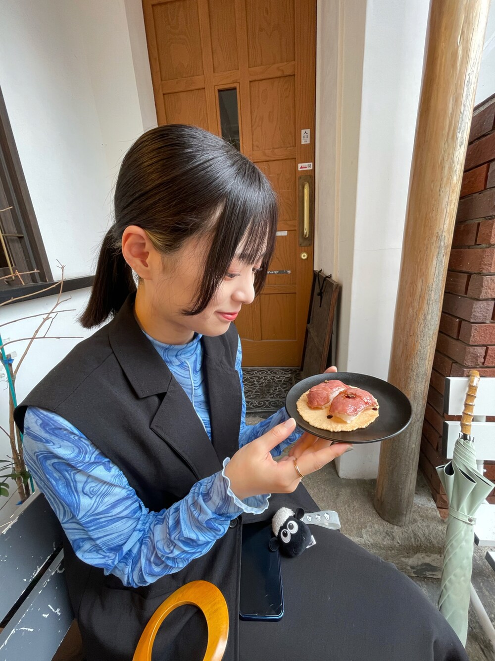 ブルー系のTシャツ/カットソー、ブラック系のスカート、ブラック系のベストを着用したレディースの秋コーディネートの2枚目の写真