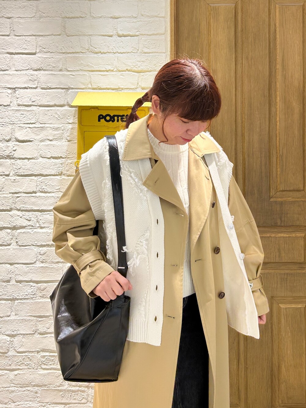 ホワイト系のベスト、ブルー系のデニムスカート、ブラック系のショルダーバッグを着用したレディースの冬コーディネートの3枚目の写真