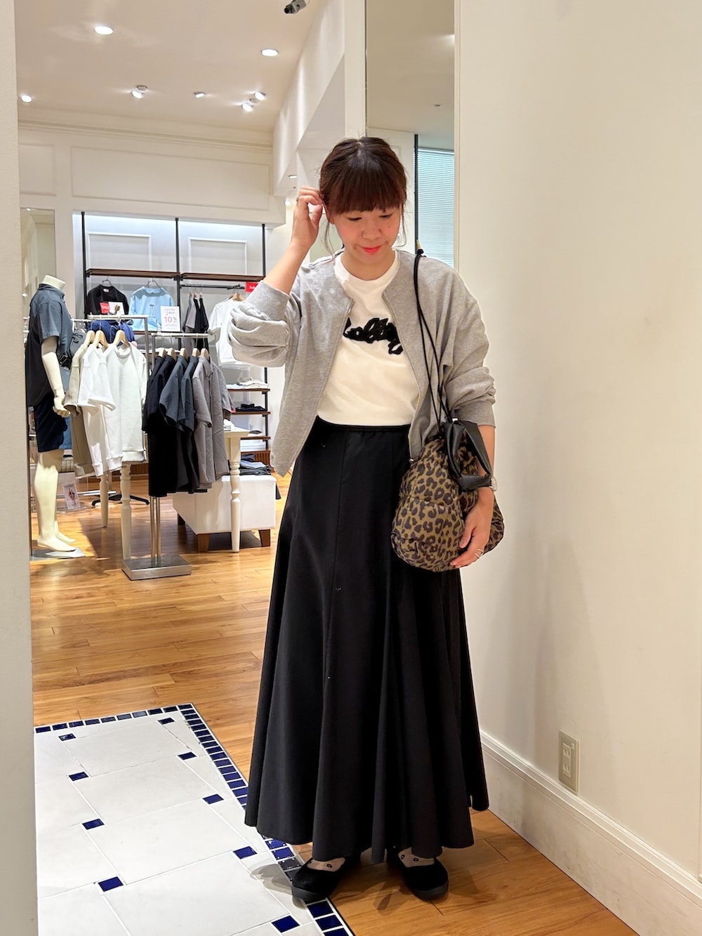 グレー系のブルゾン、ホワイト系のTシャツ/カットソー、ブラウン系のショルダーバッグを着用したレディースの夏コーディネートの2枚目の写真