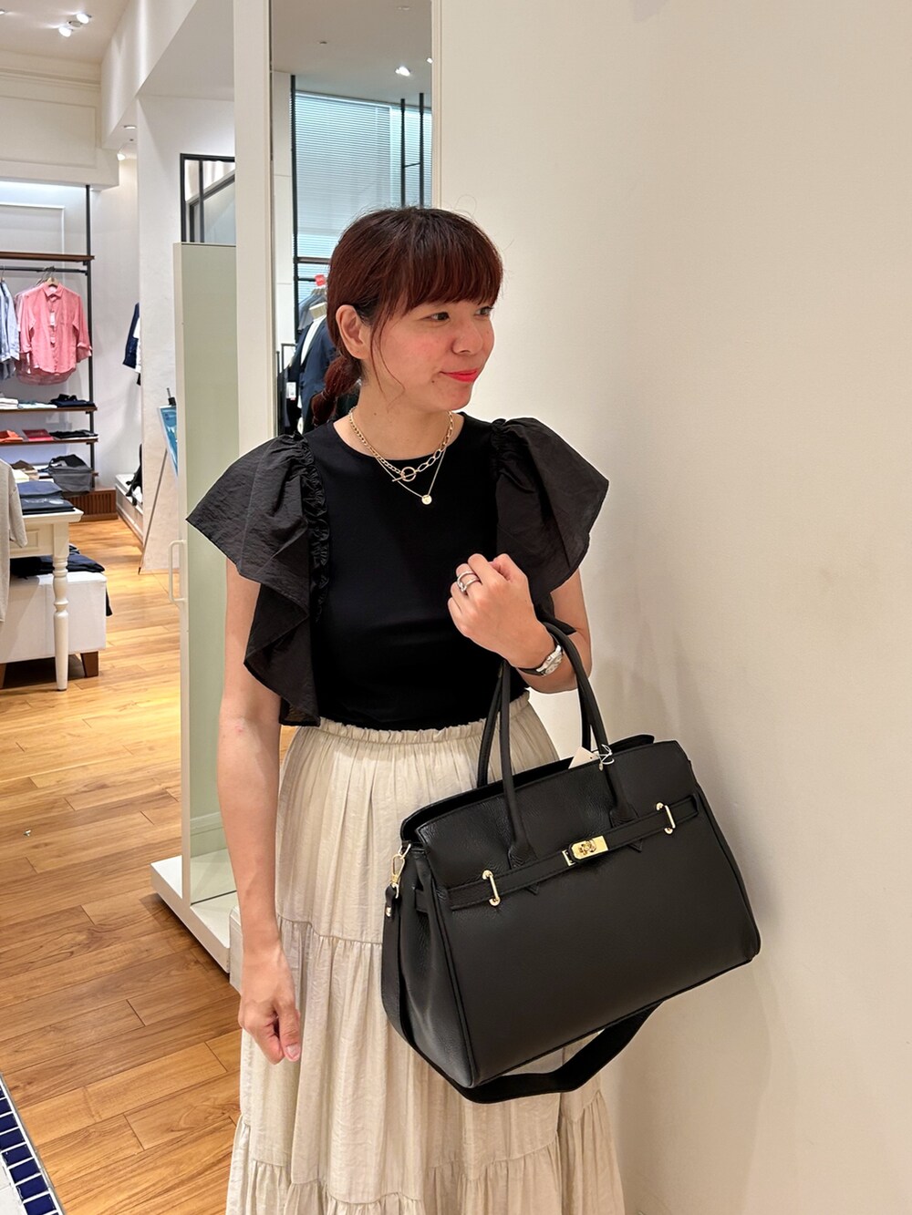 ブラック系のTシャツ/カットソー、ブラック系のショルダーバッグ、ベージュ系のスカートを着用したレディースの夏コーディネートの4枚目の写真