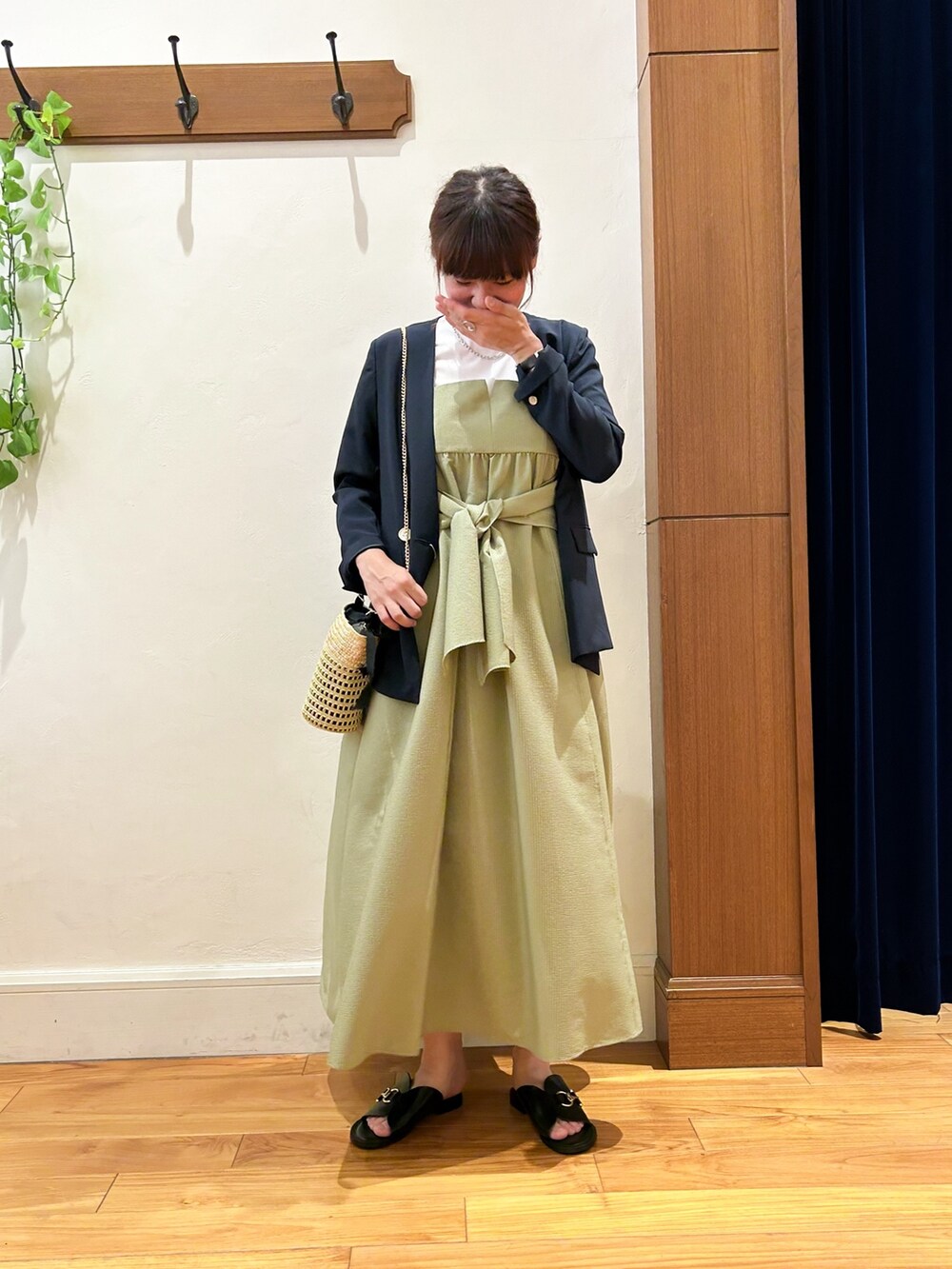 ブルー系のノーカラージャケット、グリーン系のワンピース、ベージュ系のかごバッグを着用したレディースの夏コーディネートの2枚目の写真