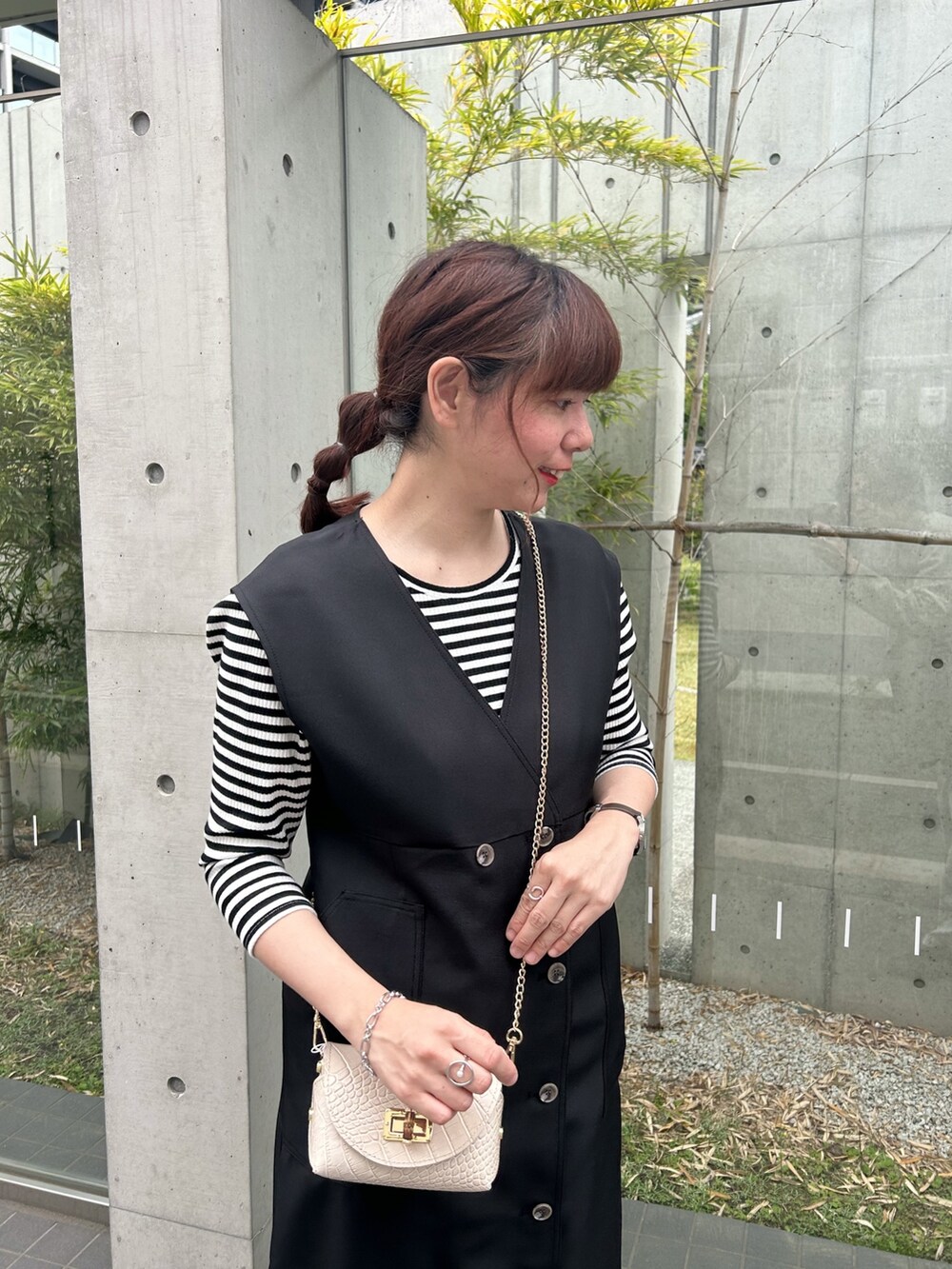ベージュ系のショルダーバッグ、ブラック系のジャンパースカート、ブラック系のTシャツ/カットソーを着用したレディースの春コーディネートの2枚目の写真