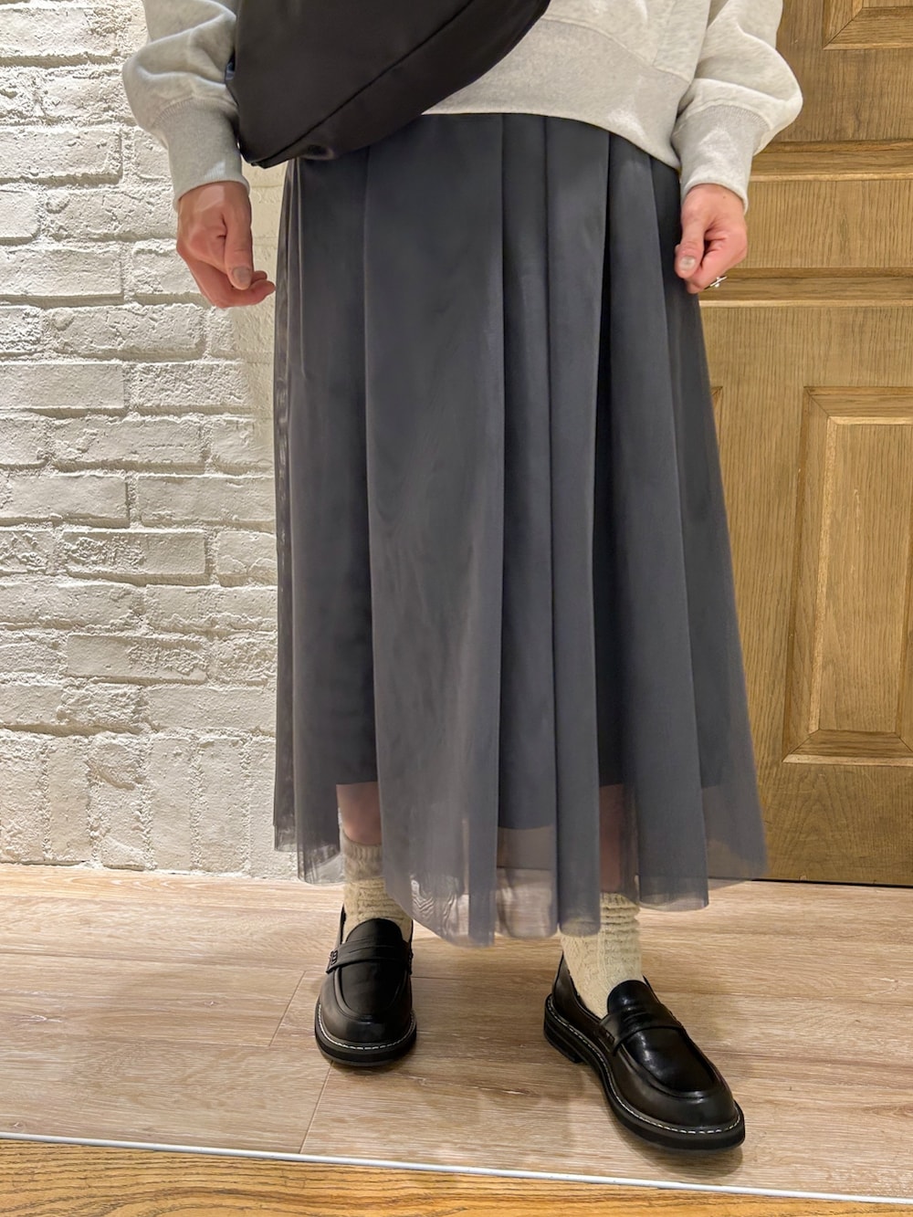 グレー系のワンピース、ブラック系のショルダーバッグ、ブラック系のローファーを着用したレディースの冬コーディネートの3枚目の写真