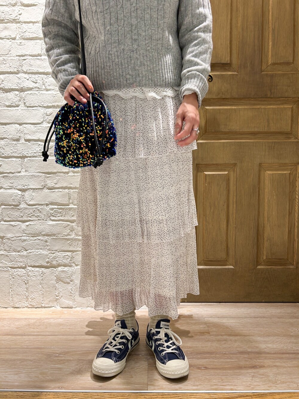 グレー系のステンカラーコート、ホワイト系のシャツ/ブラウス、グレー系のニット/セーターを着用したレディースの冬コーディネートの3枚目の写真