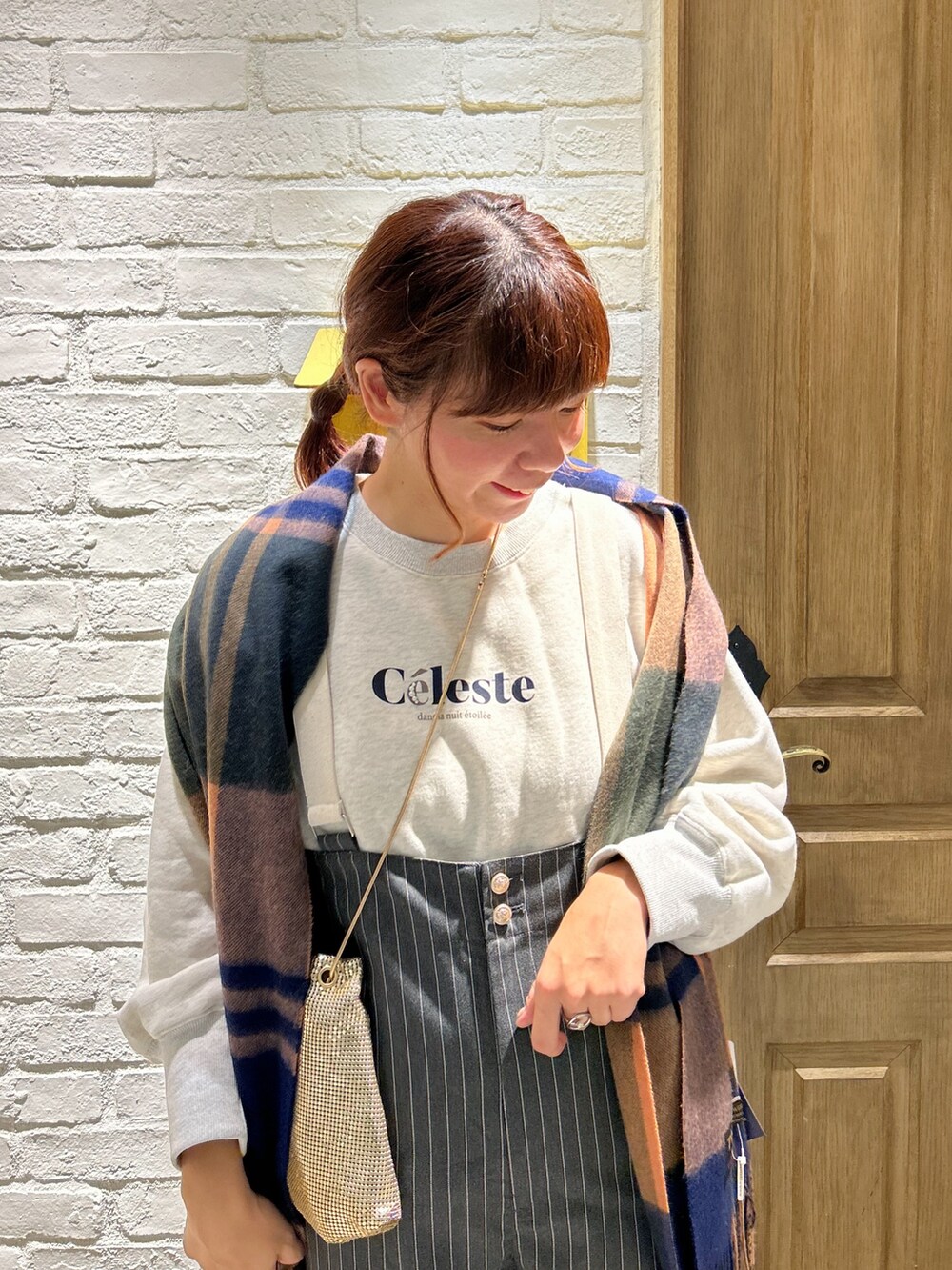 ホワイト系のスウェット、ブラック系のサロペット/オーバーオール、ゴールド系のショルダーバッグを着用したレディースの冬コーディネートの2枚目の写真