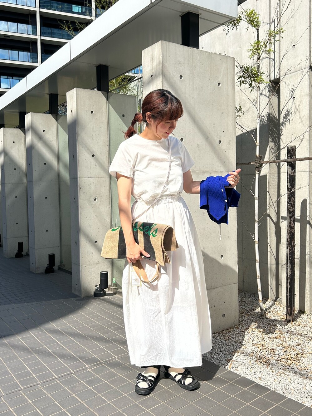 ブルー系のカーディガン/ボレロ、ホワイト系のワンピース、ブラック系のトートバッグを着用したレディースの春コーディネートの2枚目の写真