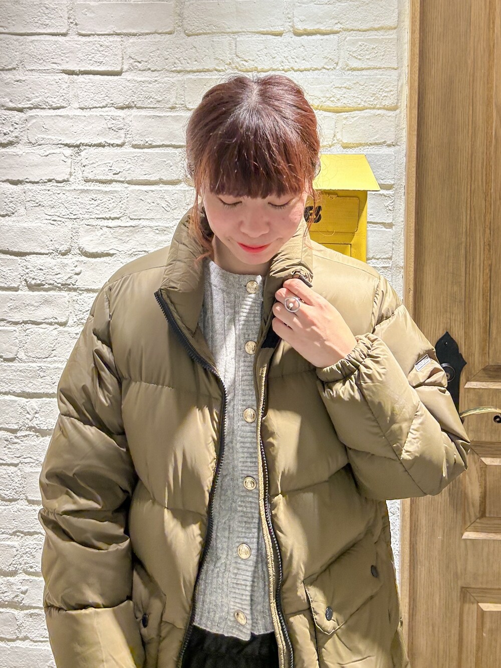 グレー系のカーディガン/ボレロ、グリーン系のダウンジャケット/コート、ブラック系のスカートを着用したレディースの冬コーディネートの2枚目の写真