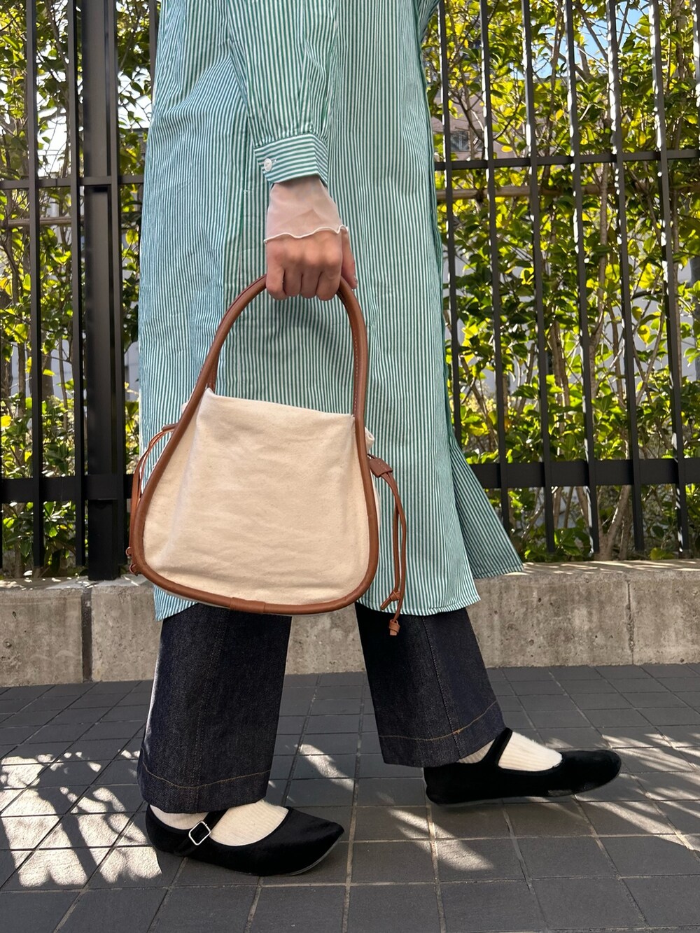 グリーン系のシャツワンピース、ブルー系のデニムパンツ、イエロー系のショルダーバッグを着用したレディースの春コーディネートの3枚目の写真