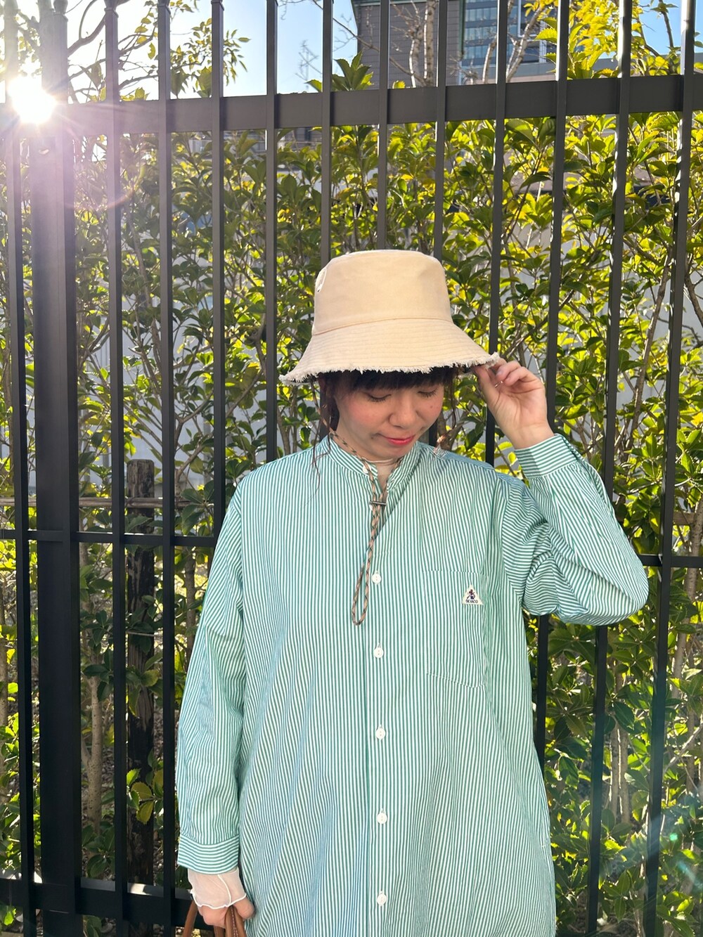 グリーン系のシャツワンピース、ブルー系のデニムパンツ、イエロー系のショルダーバッグを着用したレディースの春コーディネートの2枚目の写真