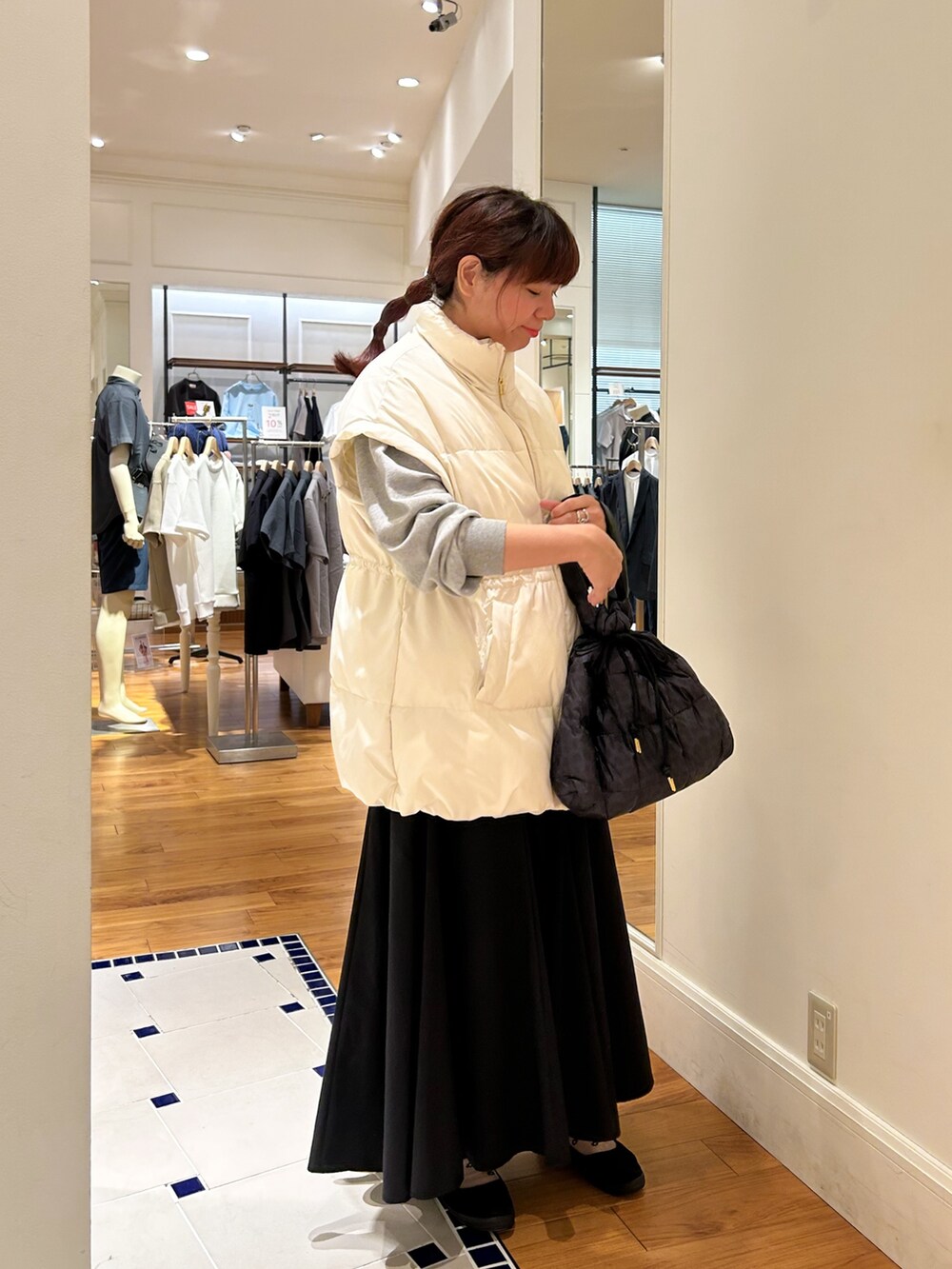 ホワイト系のダウンベスト、グレー系のブルゾン、ブラウン系のショルダーバッグを着用したレディースの夏コーディネートの2枚目の写真