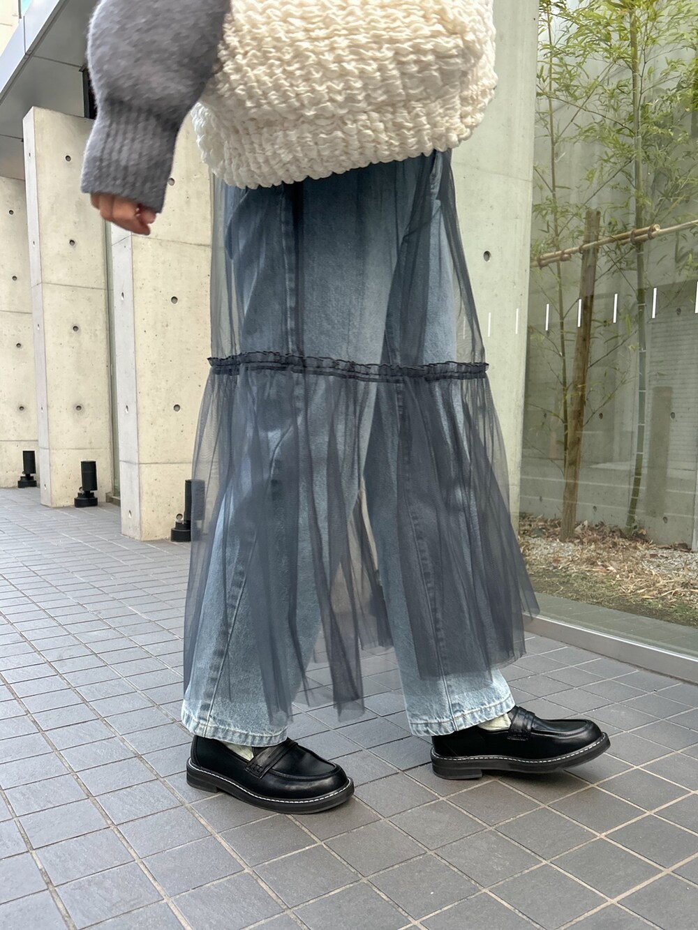 グレー系のニット/セーター、グレー系のスカート、ホワイト系のショルダーバッグを着用したレディースの冬コーディネートの4枚目の写真