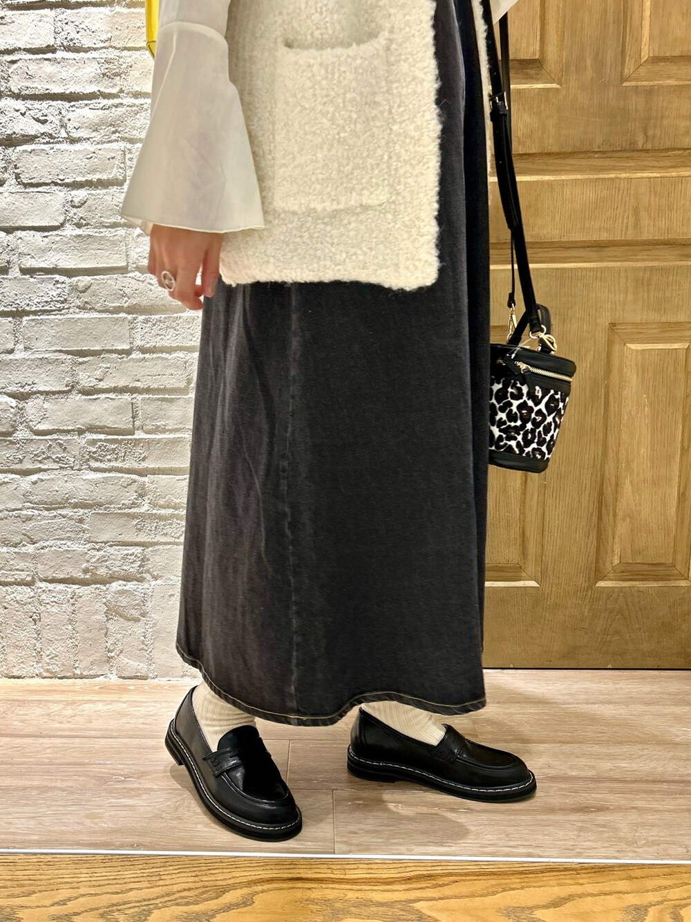 ホワイト系のベスト、ホワイト系のTシャツ/カットソー、ブラック系のワンピースを着用したレディースの秋コーディネートの3枚目の写真