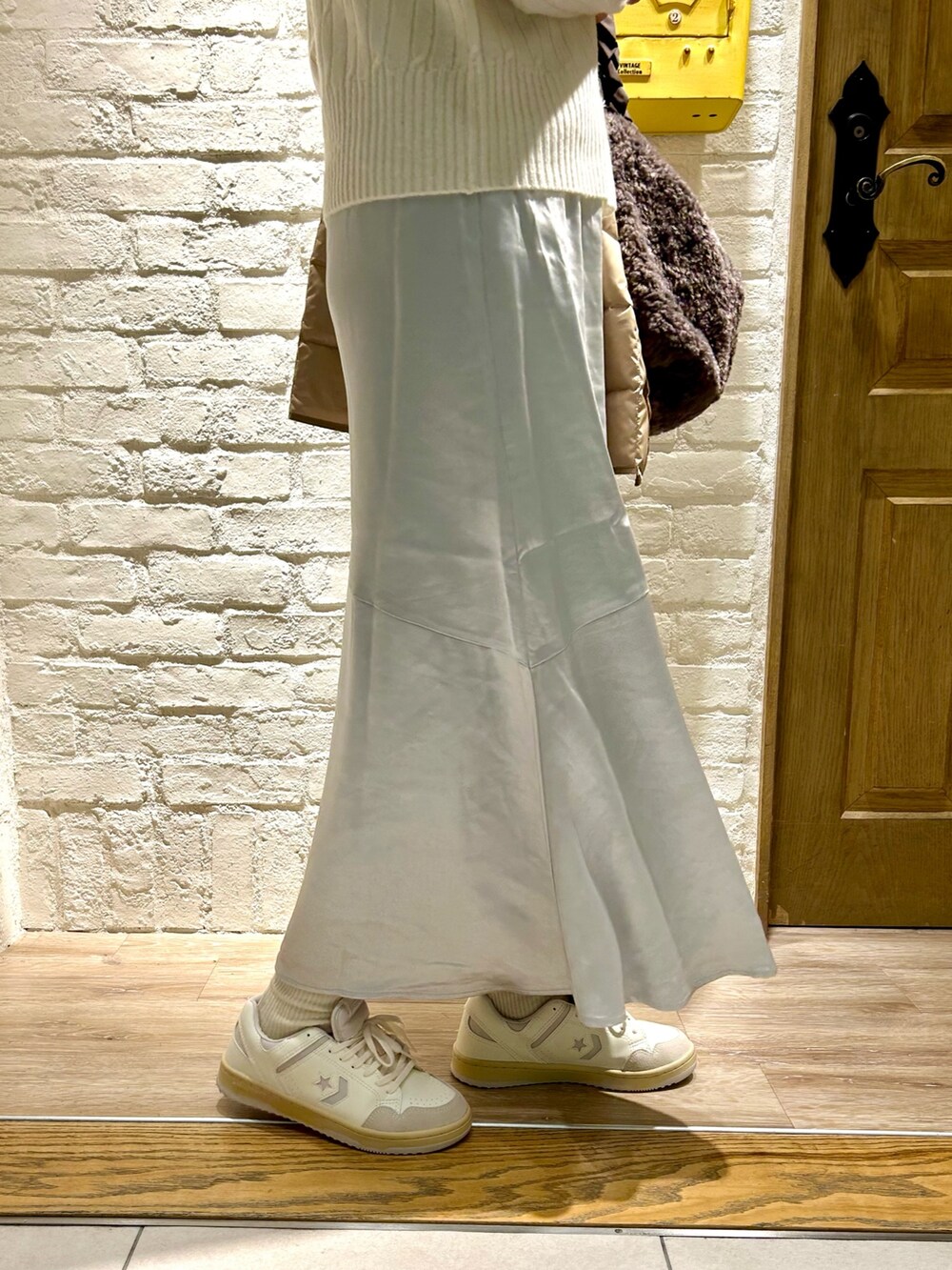 グレー系のトートバッグ、ホワイト系のニット/セーター、シルバー系のスカートを着用したレディースの秋コーディネートの3枚目の写真