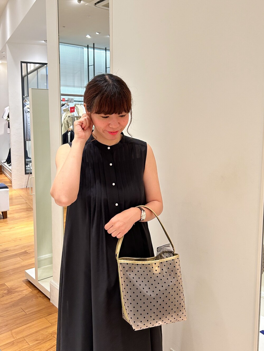 ブラック系のシャツワンピース、ベージュ系のトートバッグ、グレー系のデニムパンツを着用したレディースの夏コーディネートの3枚目の写真