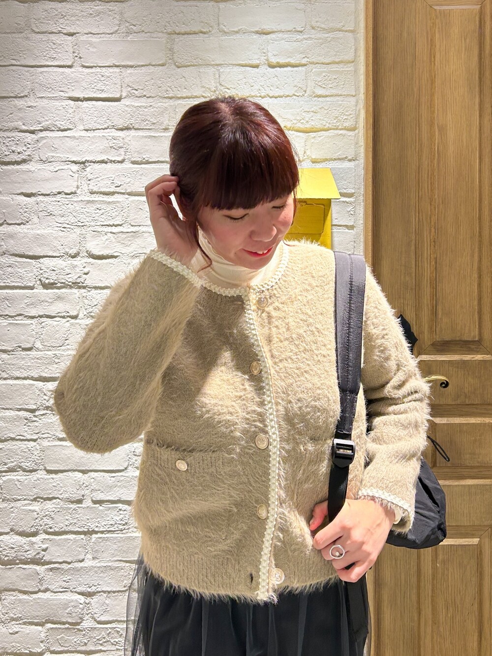 ホワイト系のTシャツ/カットソー、ベージュ系のカーディガン/ボレロ、ブラック系のバックパック/リュックを着用したレディースの冬コーディネートの2枚目の写真