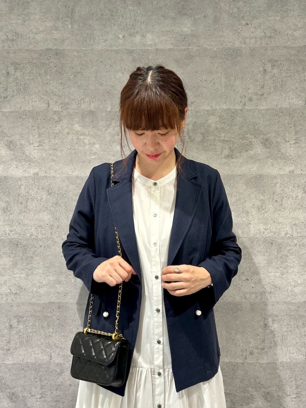 ブルー系のテーラードジャケット、ブラック系のショルダーバッグ、ホワイト系のシャツワンピースを着用したレディースの春コーディネートの2枚目の写真