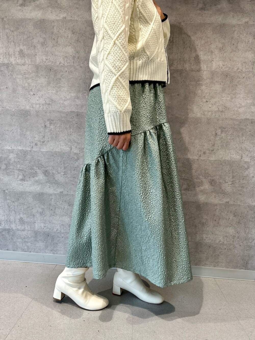 ホワイト系のカーディガン/ボレロ、ブラック系のショルダーバッグ、グリーン系のスカートを着用したレディースの冬コーディネートの3枚目の写真