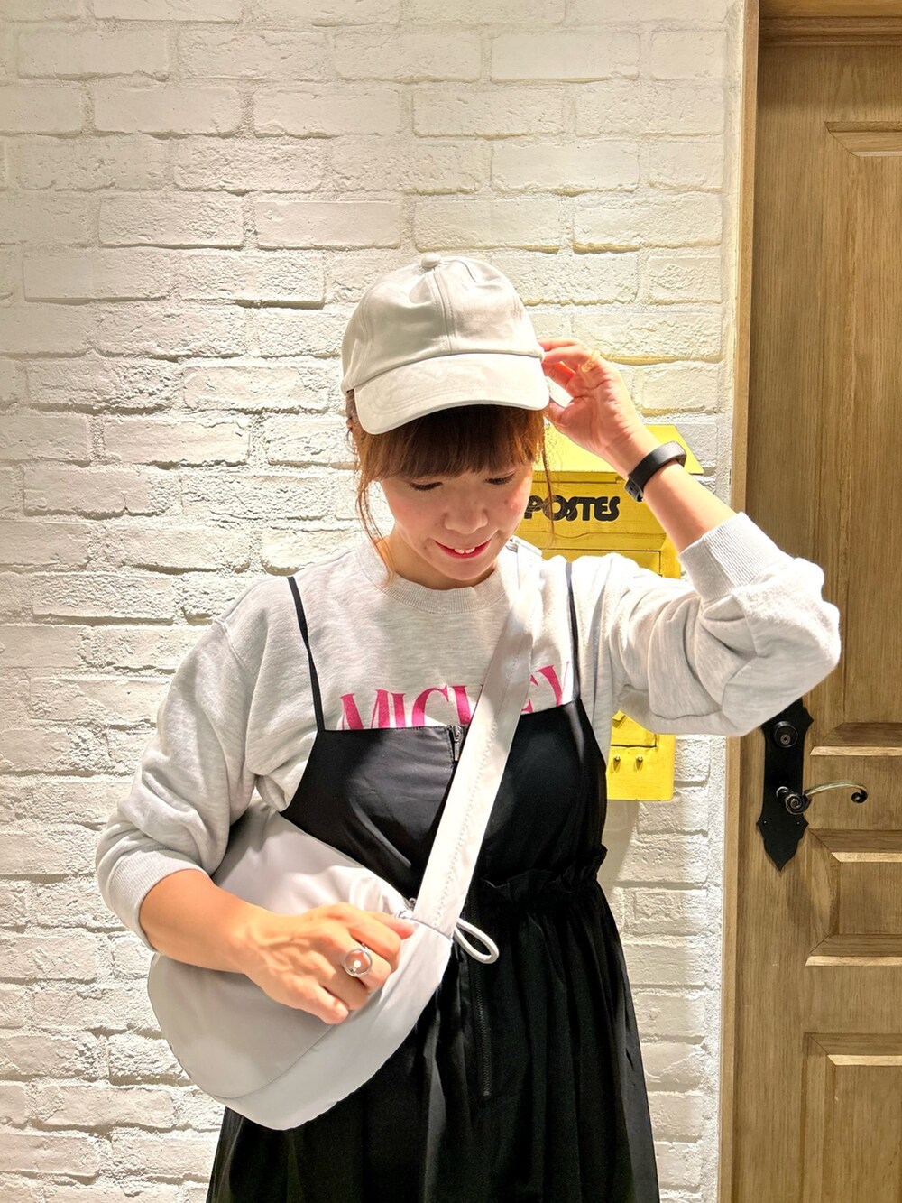 グレー系のスウェット、グレー系のショルダーバッグ、ブラック系のワンピースを着用したレディースの秋コーディネートの2枚目の写真