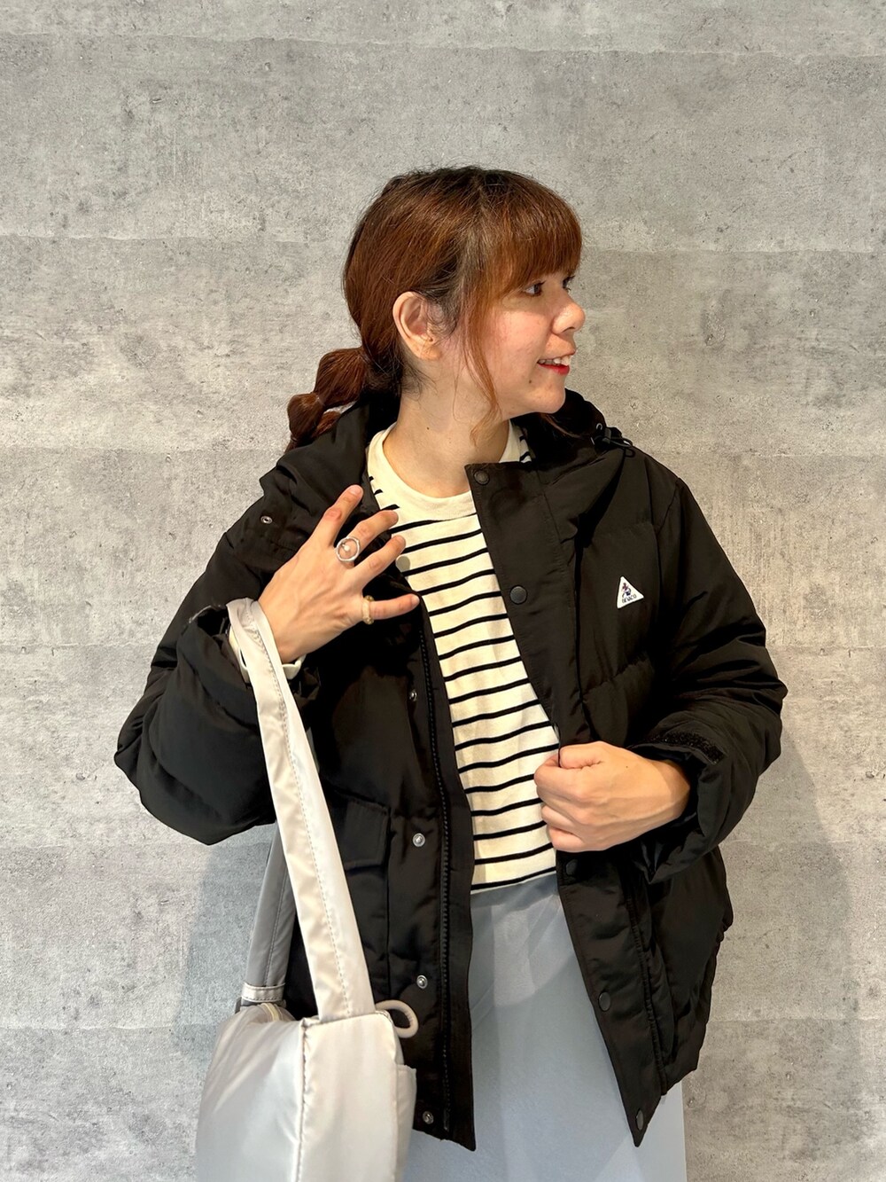 ブラック系のダウンジャケット/コート、グレー系のショルダーバッグ、ホワイト系のTシャツ/カットソーを着用したレディースの秋コーディネートの2枚目の写真