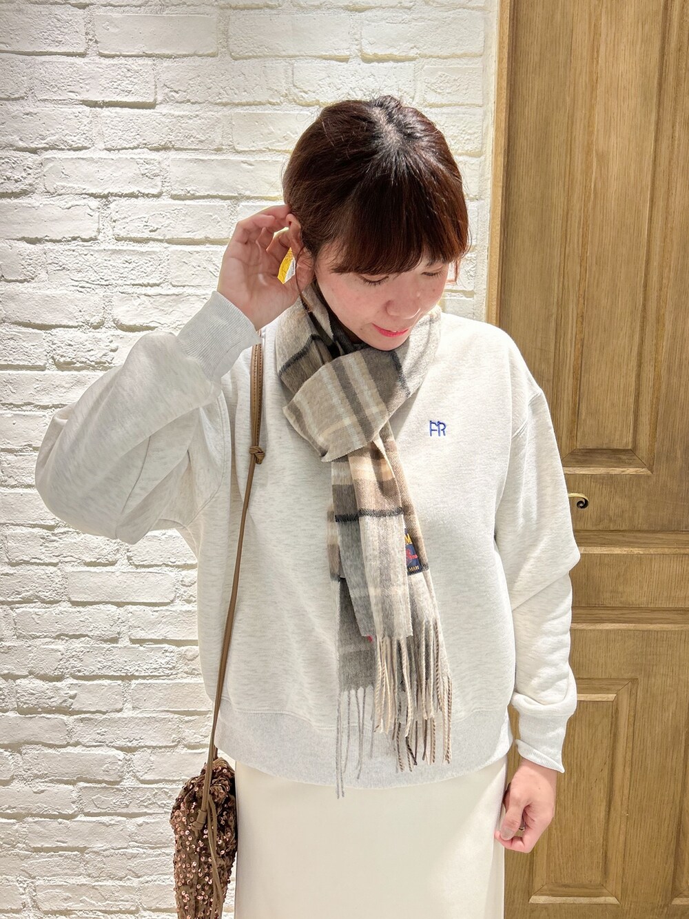 グレー系のスウェット、ゴールド系のショルダーバッグ、ホワイト系のスカートを着用したレディースの冬コーディネートの2枚目の写真