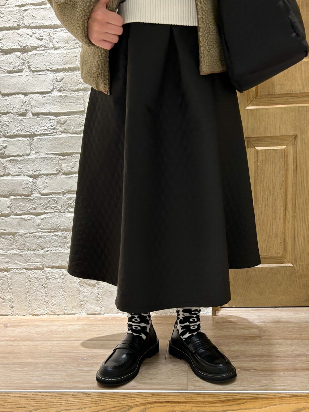 ブラック系のローファー、ブラック系のスカート、ホワイト系のベストを着用したレディースの冬コーディネートの3枚目の写真