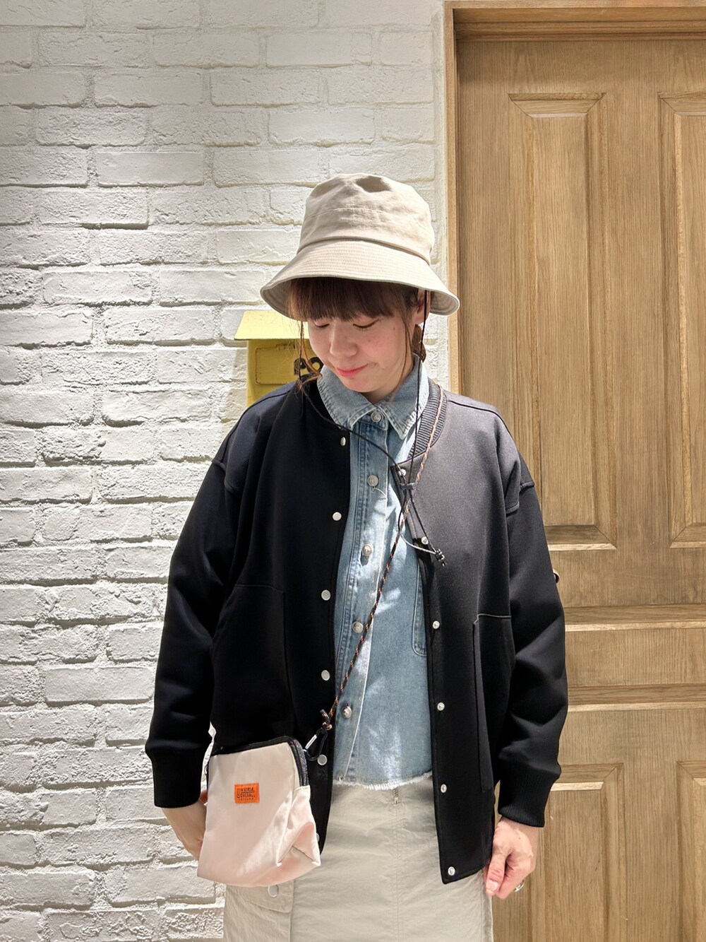 ブラック系のブルゾン、ブルー系のシャツ/ブラウス、ベージュ系のスカートを着用したレディースの春コーディネートの2枚目の写真