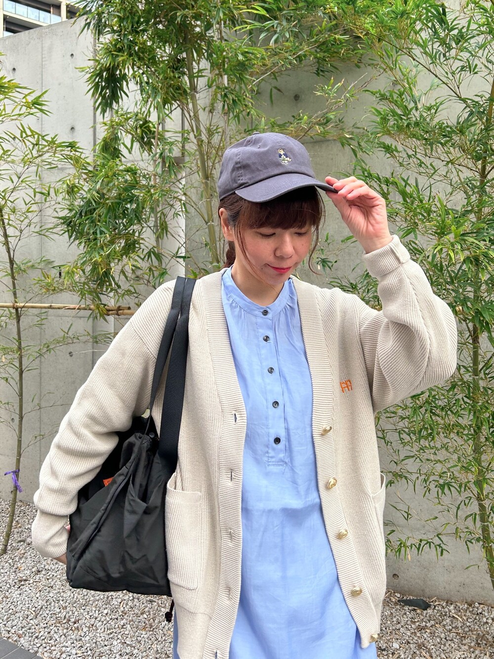 ブルー系のワンピース、ベージュ系のカーディガン/ボレロ、ブラック系のショルダーバッグを着用したレディースの春コーディネートの2枚目の写真