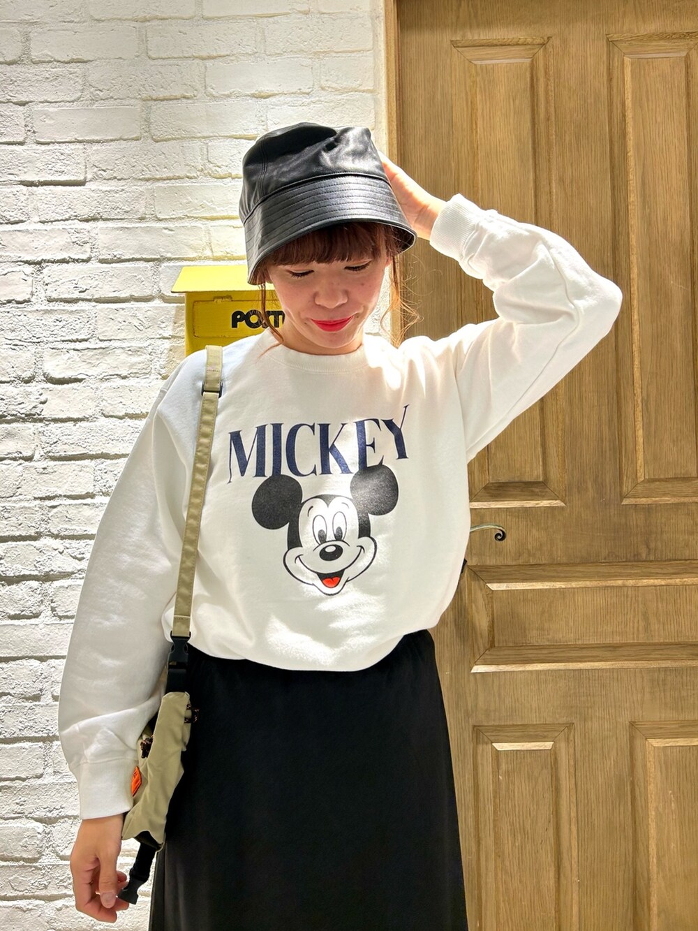 ブラック系のスカート、ベージュ系のショルダーバッグ、ホワイト系のスウェットを着用したレディースの秋コーディネートの2枚目の写真