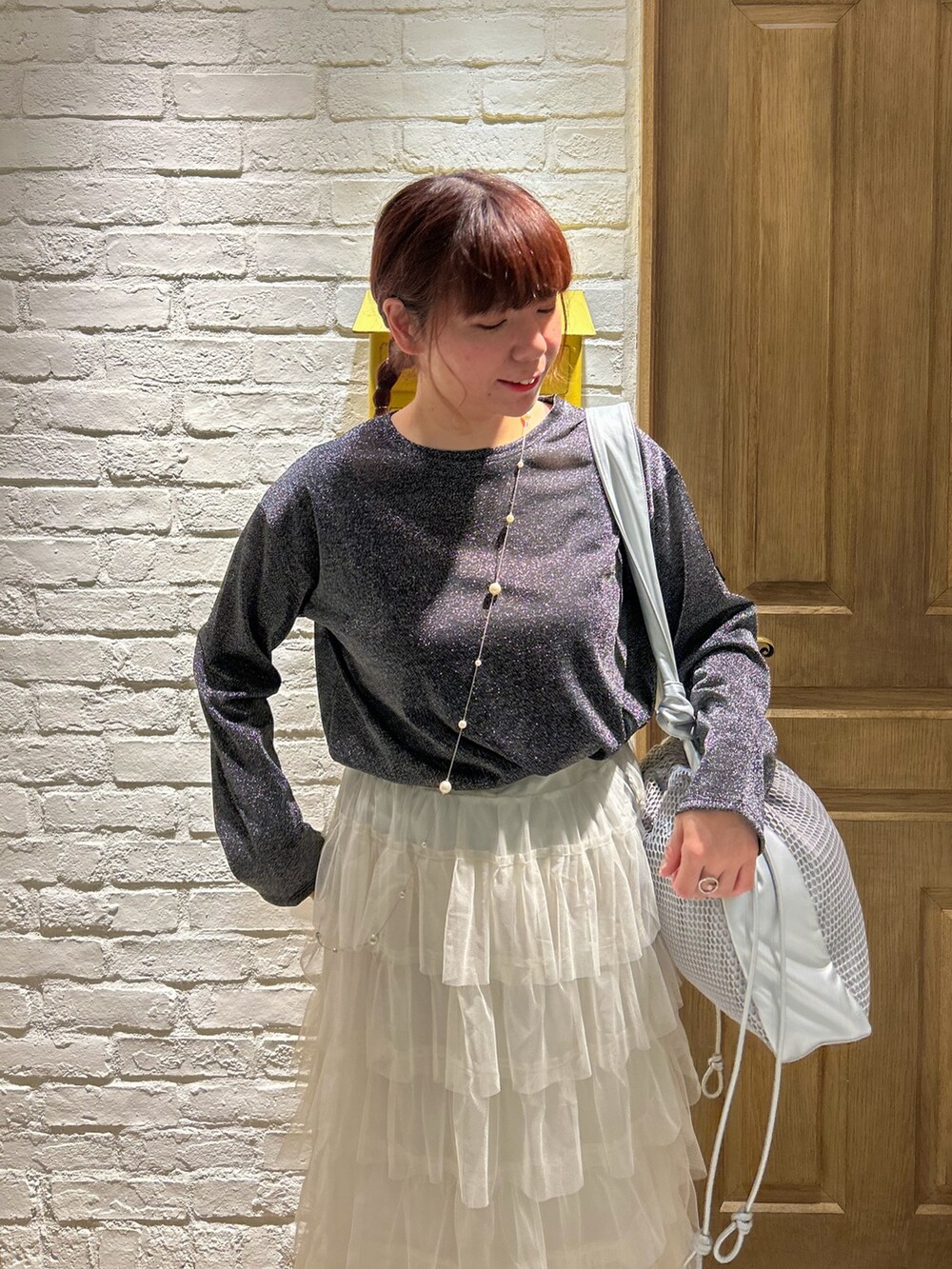 ホワイト系のスカート、ブラック系のTシャツ/カットソー、シルバー系のショルダーバッグを着用したレディースの冬コーディネートの2枚目の写真