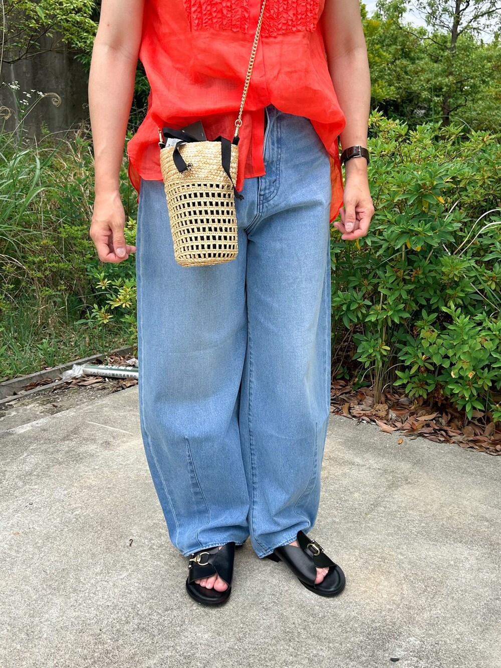 ブルー系のデニムパンツ、ベージュ系のかごバッグ、ブラック系のサンダルを着用したレディースの夏コーディネートの4枚目の写真