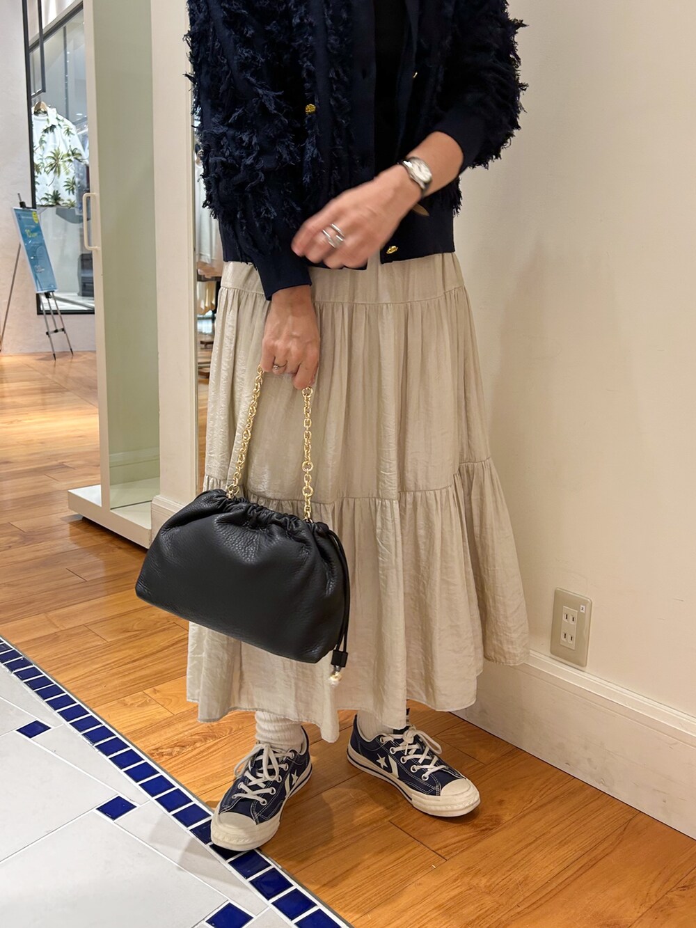 ベージュ系のスカート、ベージュ系のショルダーバッグ、ブルー系のカーディガン/ボレロを着用したレディースの夏コーディネートの4枚目の写真