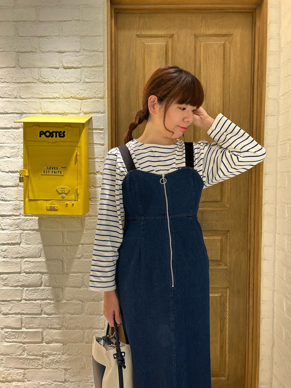 ブルー系のTシャツ/カットソー、ブラック系のジャンパースカート、イエロー系のトートバッグを着用したレディースの春コーディネートの2枚目の写真