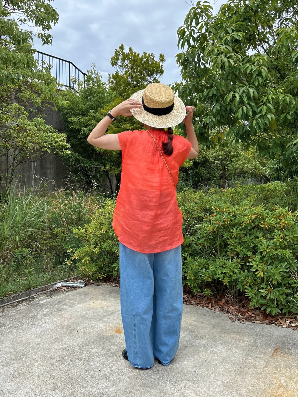 ブルー系のデニムパンツ、ベージュ系のかごバッグ、ブラック系のサンダルを着用したレディースの夏コーディネートの2枚目の写真