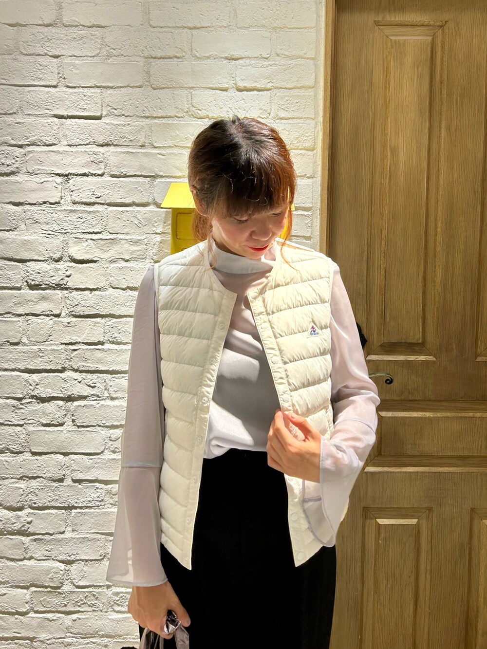 ゴールド系のトートバッグ、ブラック系のその他パンツ、ホワイト系のダウンベストを着用したレディースの秋コーディネートの2枚目の写真