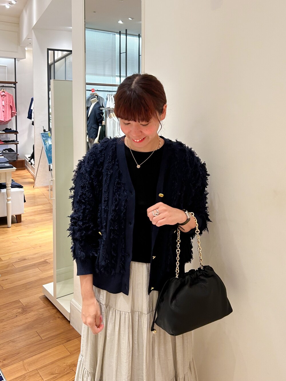 ベージュ系のスカート、ベージュ系のショルダーバッグ、ブルー系のカーディガン/ボレロを着用したレディースの夏コーディネートの3枚目の写真