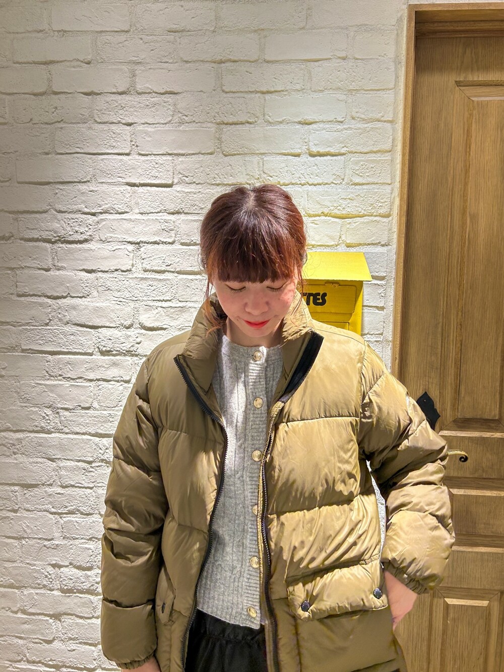 グレー系のカーディガン/ボレロ、グリーン系のダウンジャケット/コート、ブラック系のスカートを着用したレディースの冬コーディネートの2枚目の写真