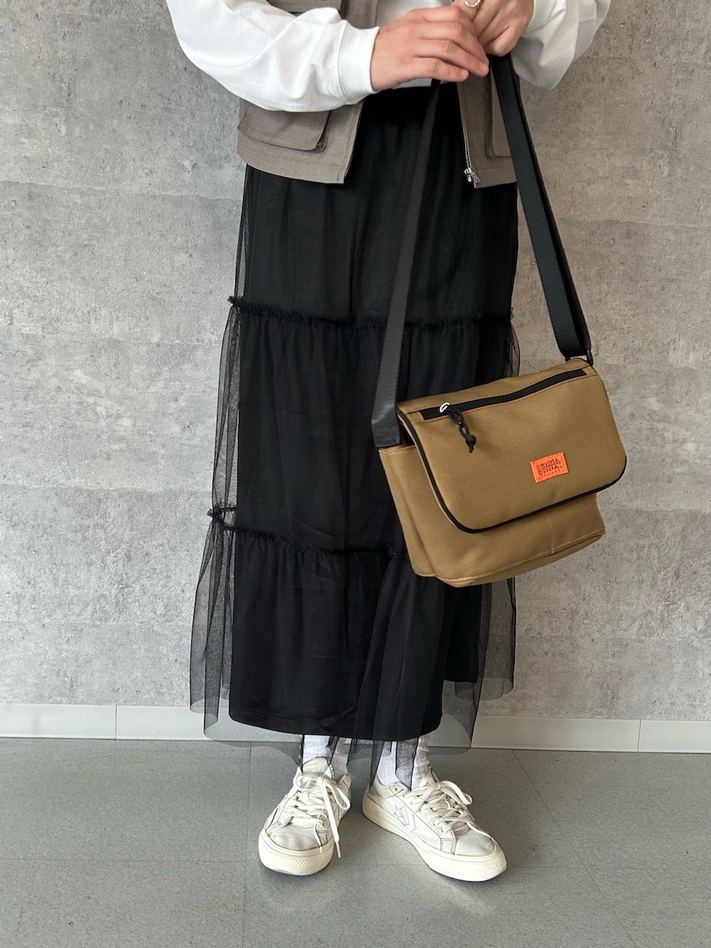 ベージュ系のベスト、ホワイト系のTシャツ/カットソー、ブラック系のスカートを着用したレディースの春コーディネートの3枚目の写真