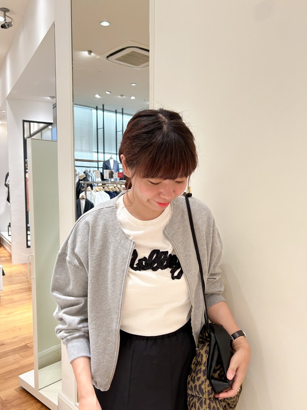 グレー系のブルゾン、ホワイト系のTシャツ/カットソー、ブラウン系のショルダーバッグを着用したレディースの夏コーディネートの3枚目の写真