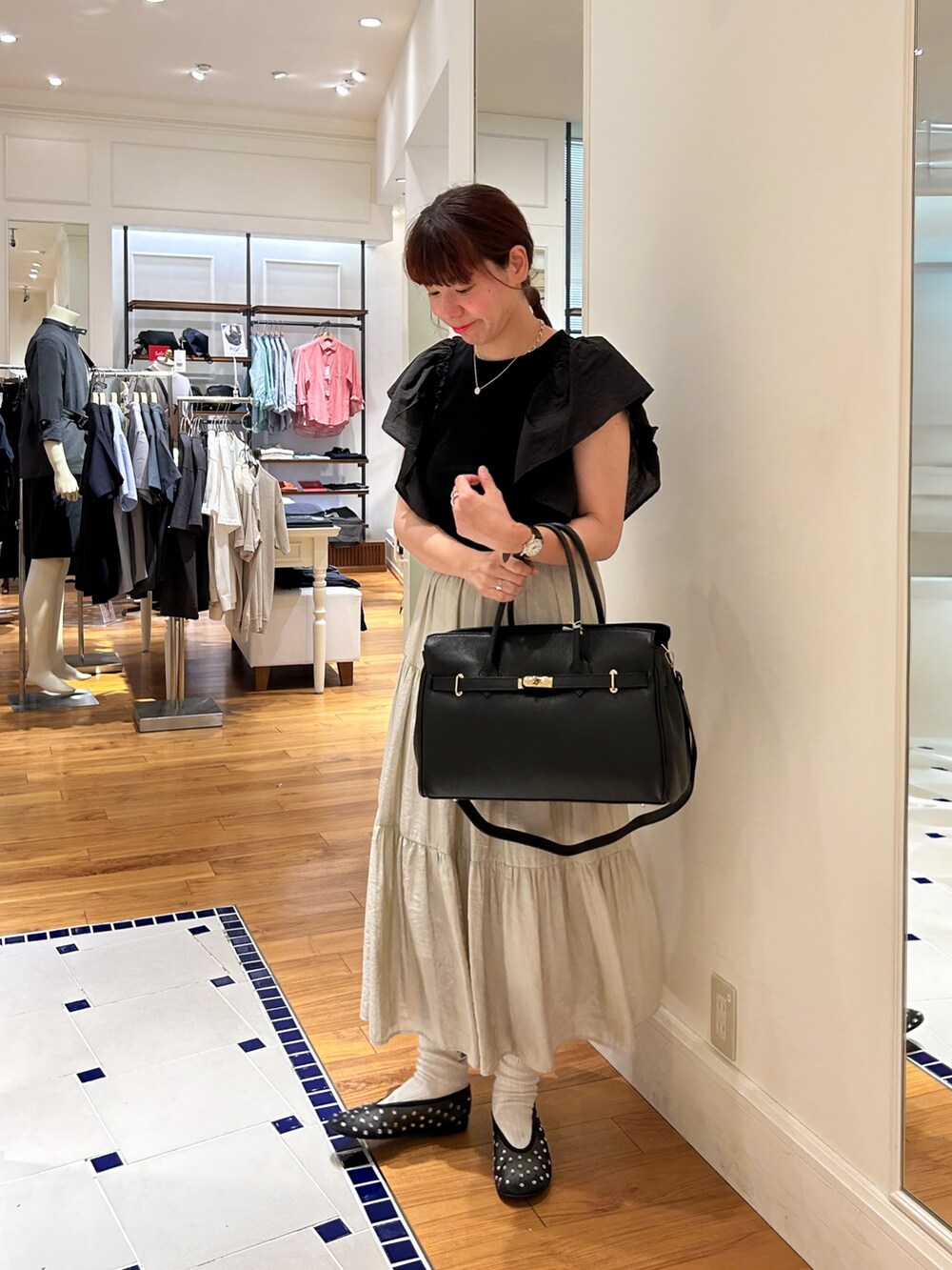 ブラック系のTシャツ/カットソー、ブラック系のショルダーバッグ、ベージュ系のスカートを着用したレディースの夏コーディネートの3枚目の写真