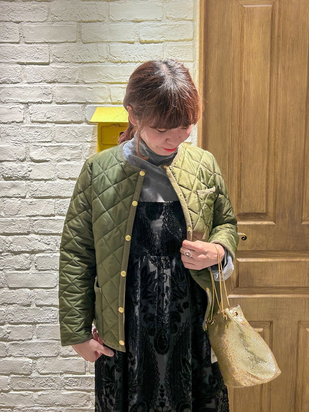 グレー系のTシャツ/カットソー、ブラック系のワンピース、ゴールド系のショルダーバッグを着用したレディースの秋コーディネートの2枚目の写真