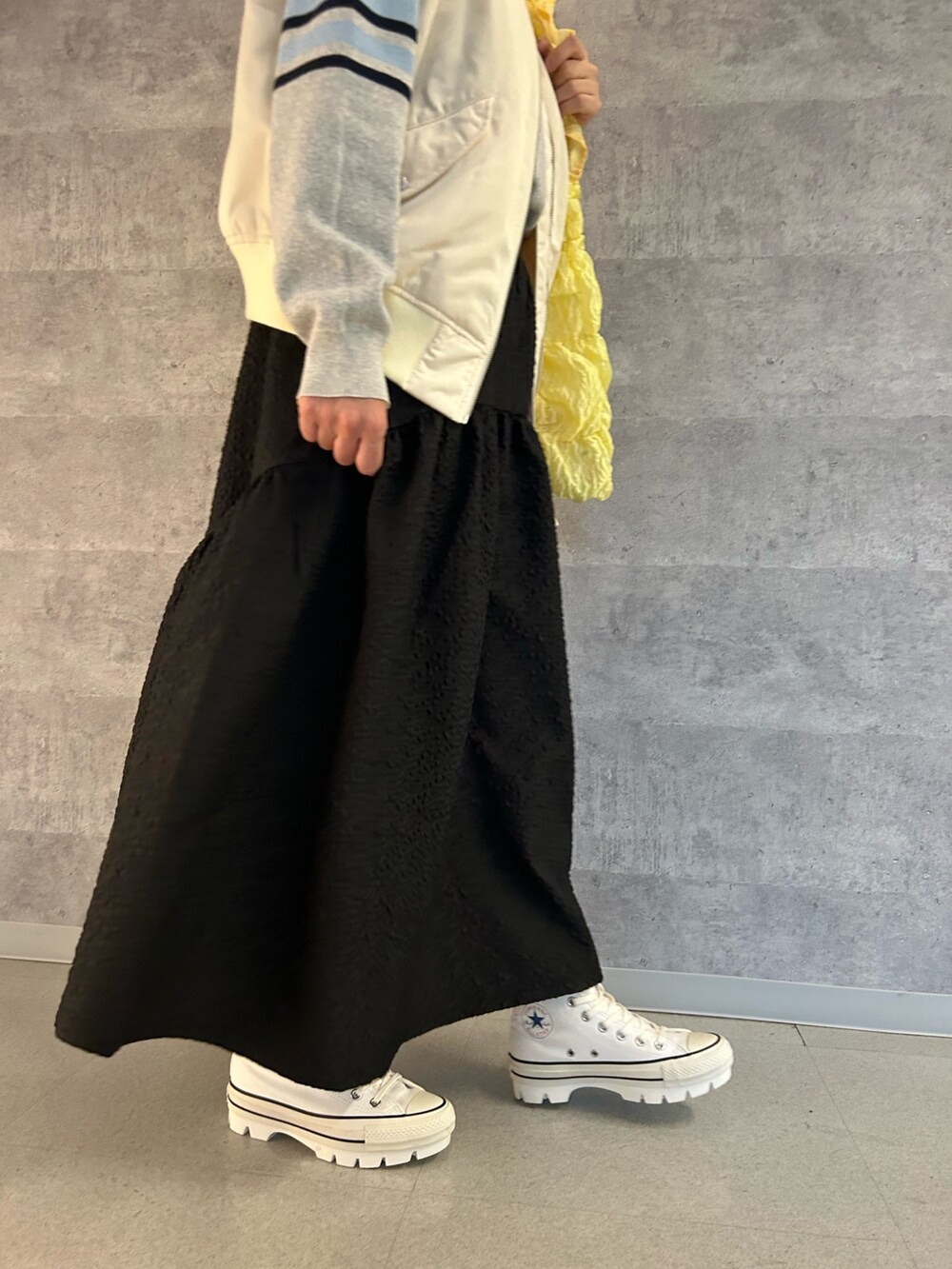 ホワイト系のスニーカー、ブラック系のスカート、イエロー系のトートバッグを着用したレディースの冬コーディネートの4枚目の写真