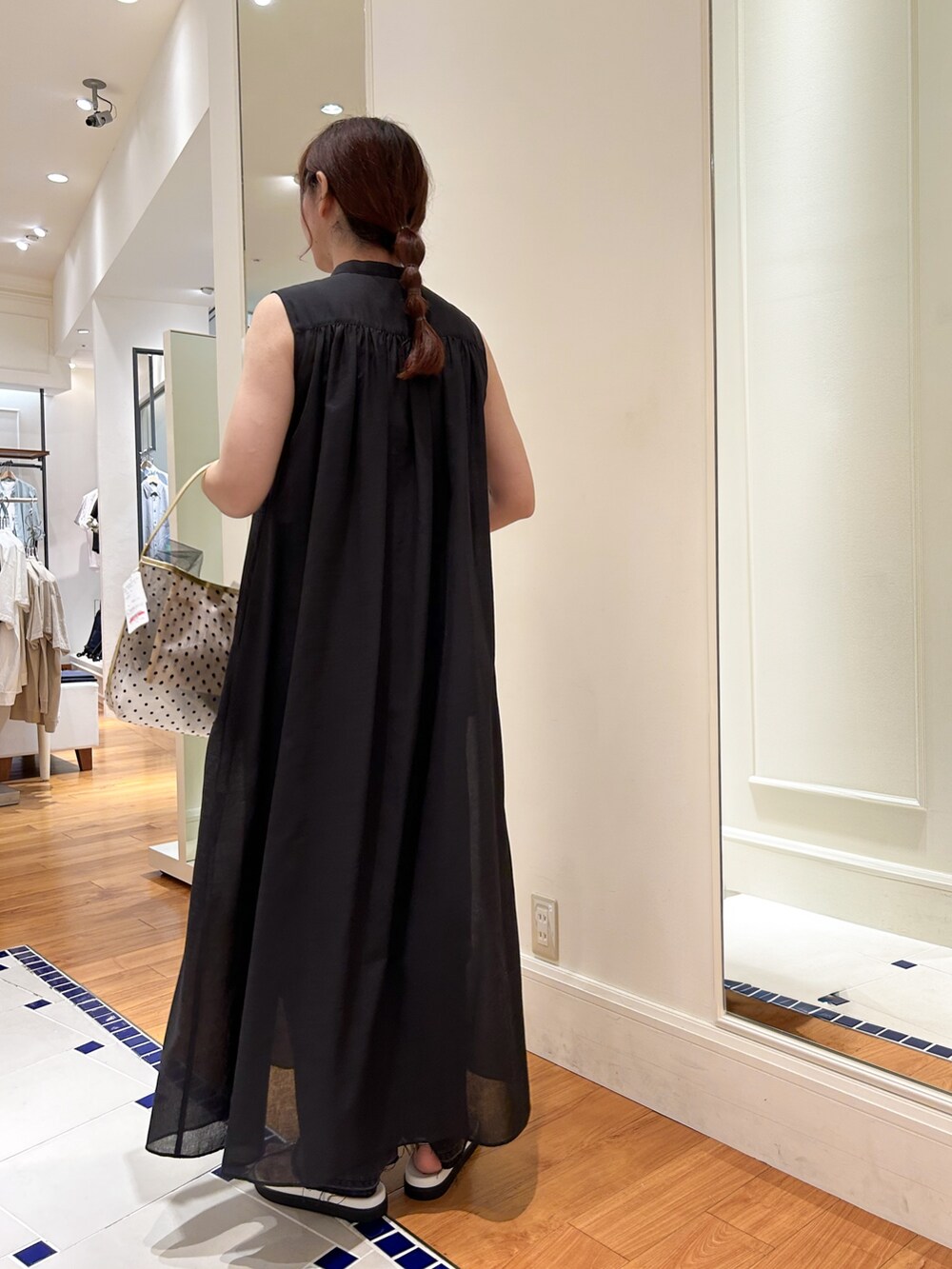 ブラック系のシャツワンピース、ベージュ系のトートバッグ、グレー系のデニムパンツを着用したレディースの夏コーディネートの4枚目の写真