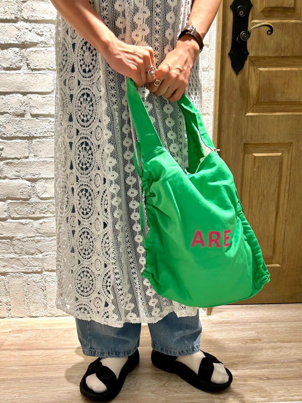 ブラック系のスニーカー、ホワイト系のTシャツ/カットソー、ブルー系のデニムパンツを着用したレディースの夏コーディネートの3枚目の写真