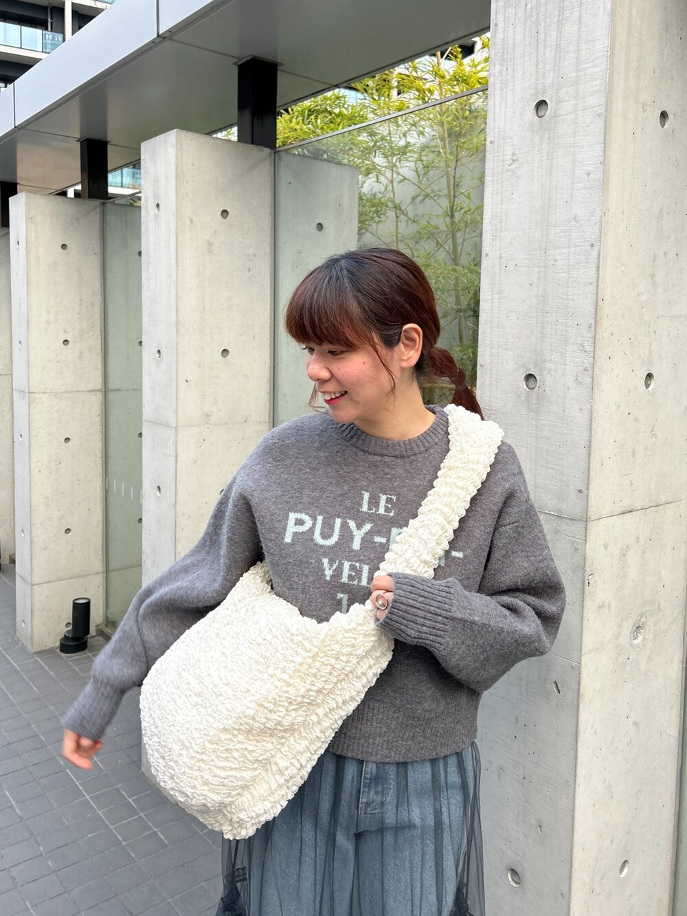 グレー系のニット/セーター、グレー系のスカート、ホワイト系のショルダーバッグを着用したレディースの冬コーディネートの3枚目の写真