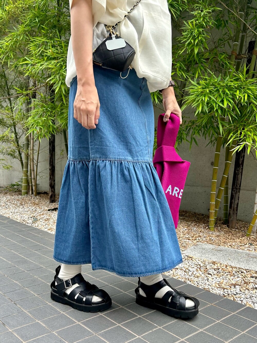 ブルー系のデニムスカート、ピンク系のトートバッグ、パープル系のTシャツ/カットソーを着用したレディースの夏コーディネートの3枚目の写真