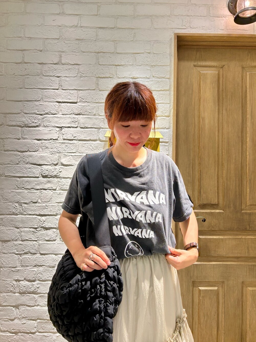 ブラック系のショルダーバッグ、ベージュ系のスカート、グレー系のTシャツ/カットソーを着用したレディースの夏コーディネートの2枚目の写真