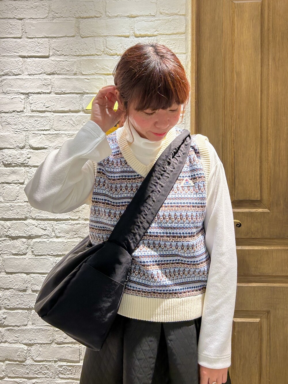 ブラック系のローファー、ブラック系のスカート、ホワイト系のベストを着用したレディースの冬コーディネートの2枚目の写真