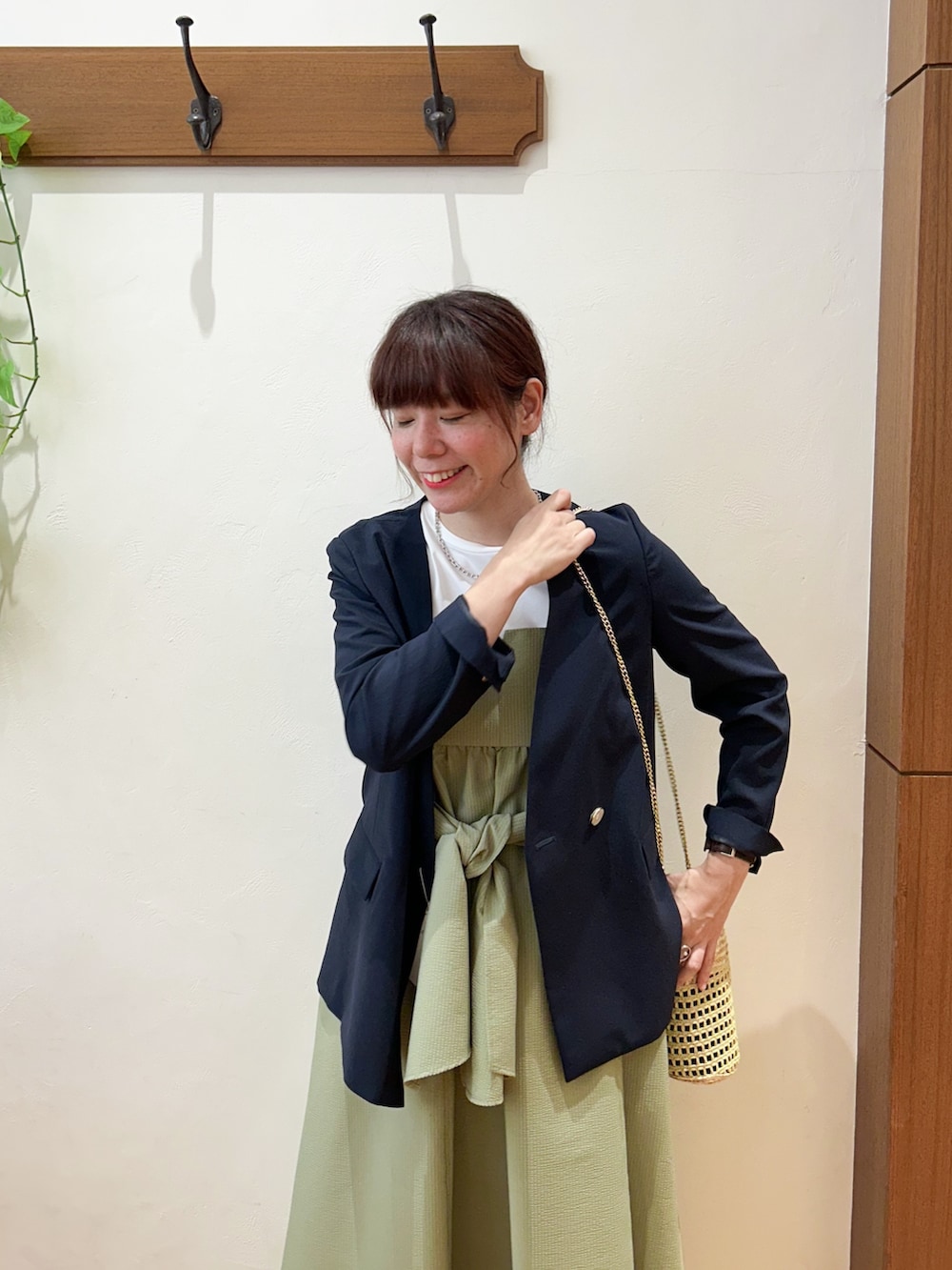 ブルー系のノーカラージャケット、グリーン系のワンピース、ベージュ系のかごバッグを着用したレディースの夏コーディネートの3枚目の写真